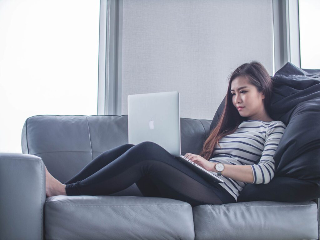 Young girl laying on couch with laptop