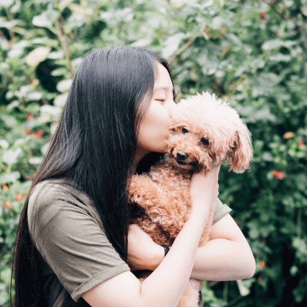 Asian girl outdoors kissing her dog, portraying outpatient teen anxiety treatment programs