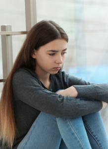 Young teen girl sitting and looking anxious