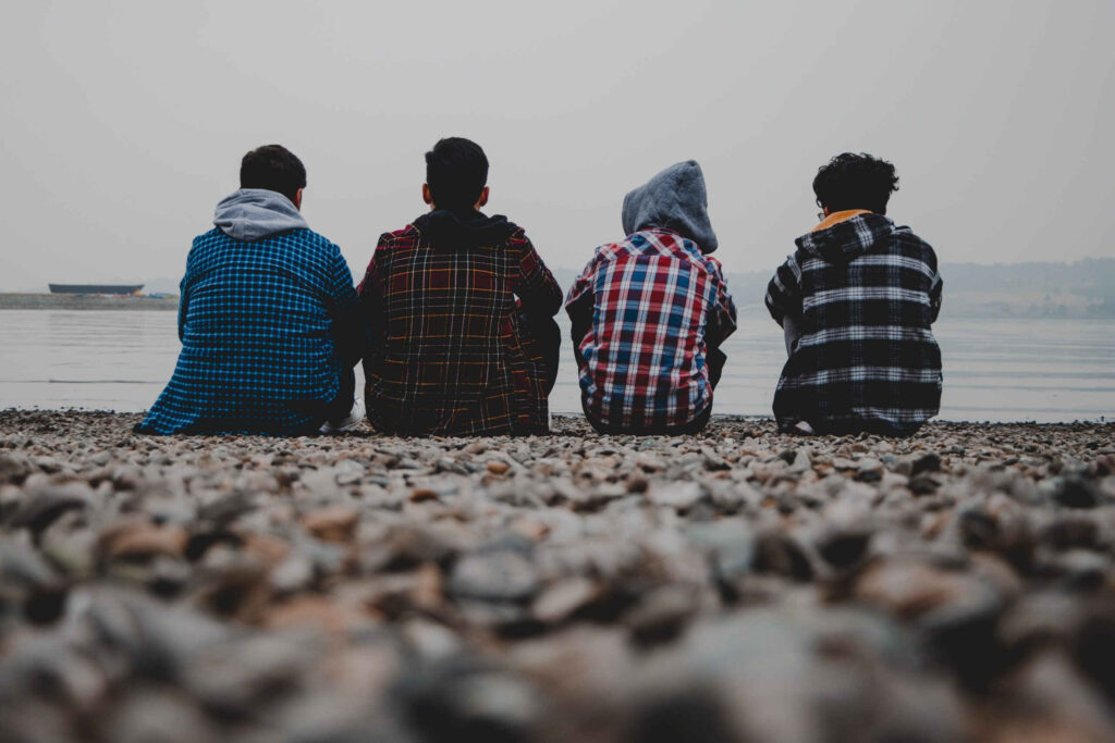 teen boys sit on a beach discussing mental health and addiction issues