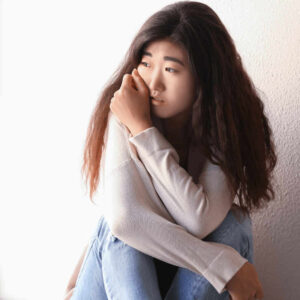 Sad Asian young teen girl crouching on the floor