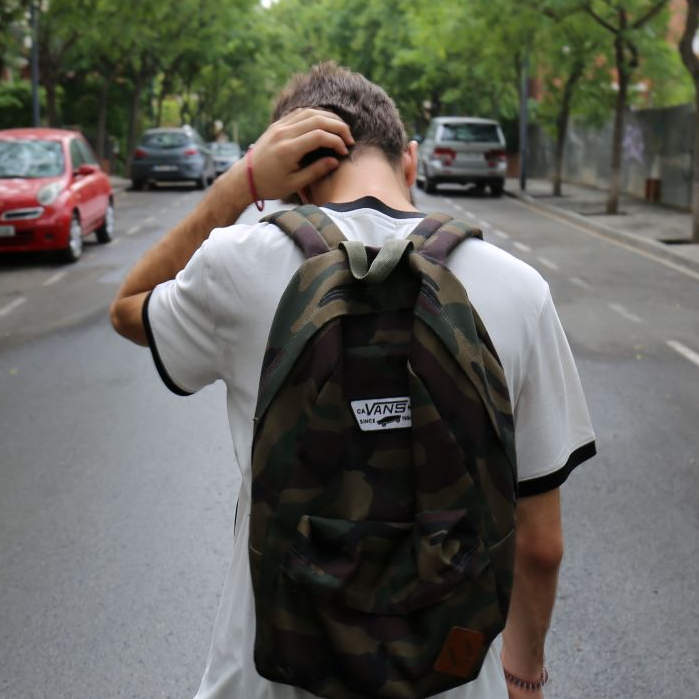 Young boy wearing a backpack with back turned dealing with mental health issues as a teen