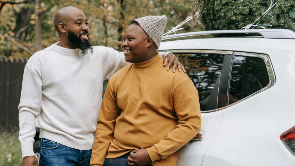 father and son share a moment of happiness outside by a white car