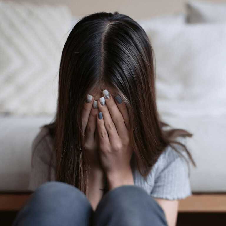 young girl sit at the end of the bed crying due to the struggles of mental health