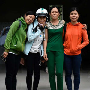 a mother and 3 young daughters all stand hugging each other