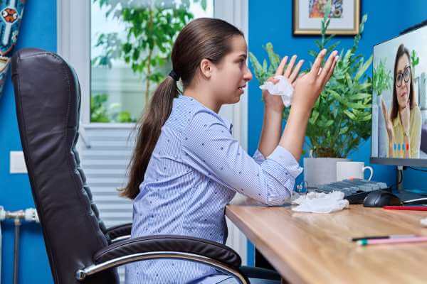 Teen girl crying while talking to an online therapist