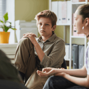 Pre-teen boy quietly listening to a therapist during a group session