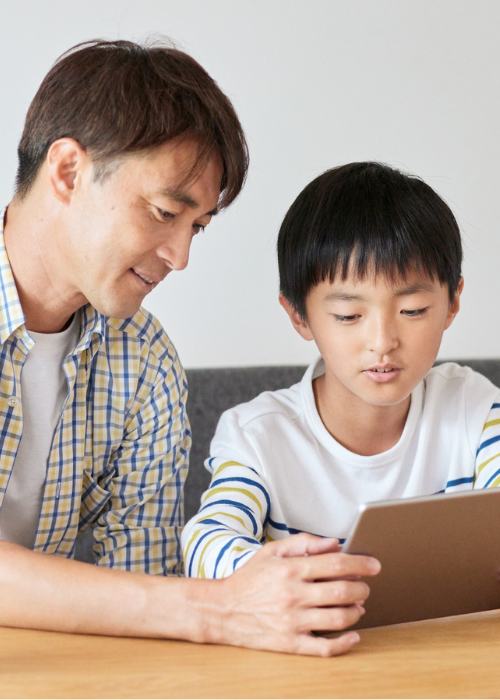 A father and son use a tablet for an online mental health therapy session