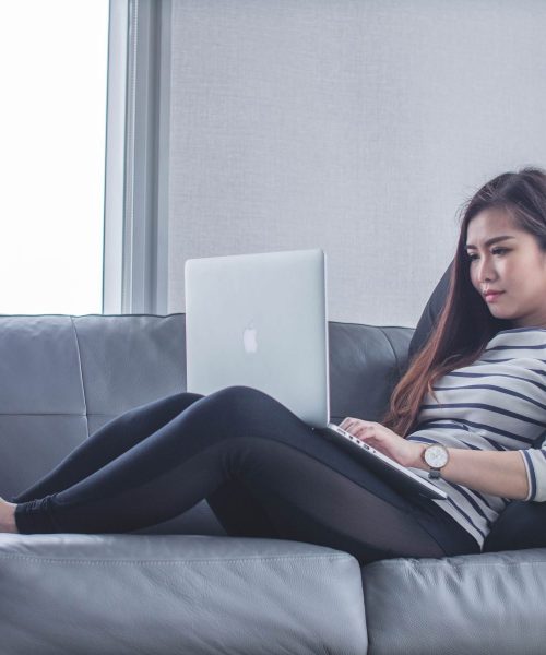 Young girl laying on couch with laptop
