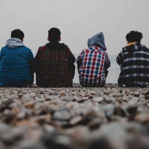 teen boys sit on a beach discussing mental health and addiction issues