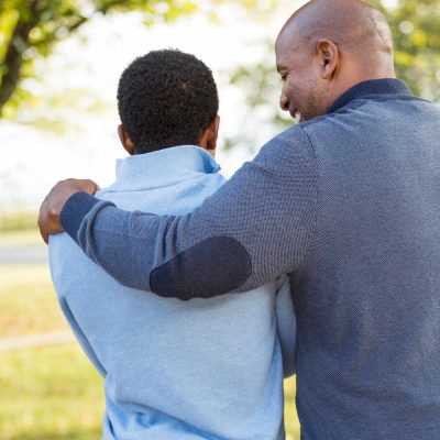 African American father walking outdoors with his son