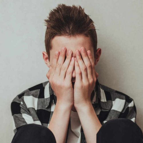 Young boy with his hands to his face as he struggles with mental health issues in Dallas, TX