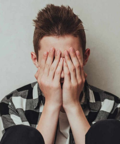 Young boy with his hands to his face as he struggles with mental health issues in Dallas, TX