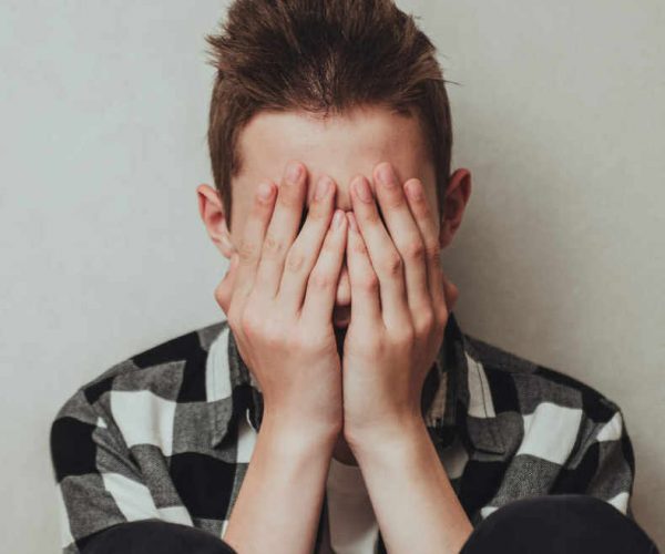 Young boy with his hands to his face as he struggles with mental health issues in Dallas, TX