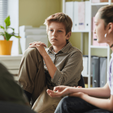 Pre-teen boy quietly listening to a therapist during a group session