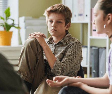 Pre-teen boy quietly listening to a therapist during a group session
