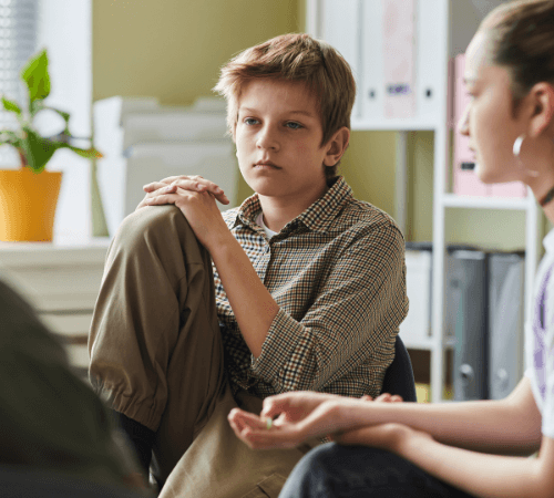 Pre-teen boy quietly listening to a therapist during a group session