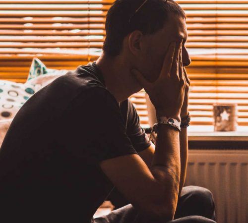 young man sits in dark room struggling with teen anger and needing anger management