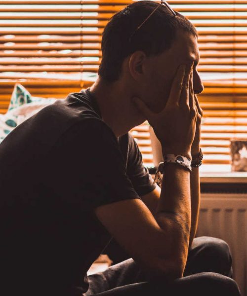 young man sits in dark room struggling with teen anger and needing anger management