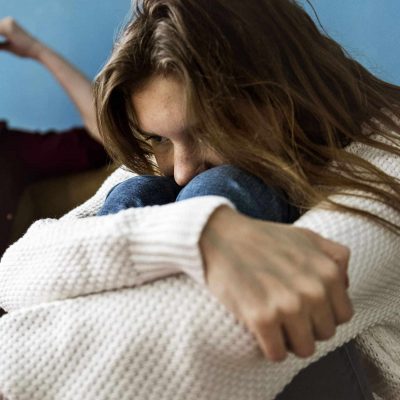 Young girl with her head in her knees upset about the struggles of being a teen