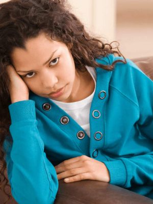 young girl sits on the couch struggling with mental health issues