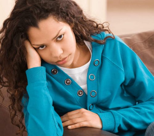 young girl sits on the couch struggling with mental health issues