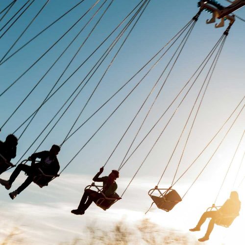 teens riding a swing ride at a fair as dusk