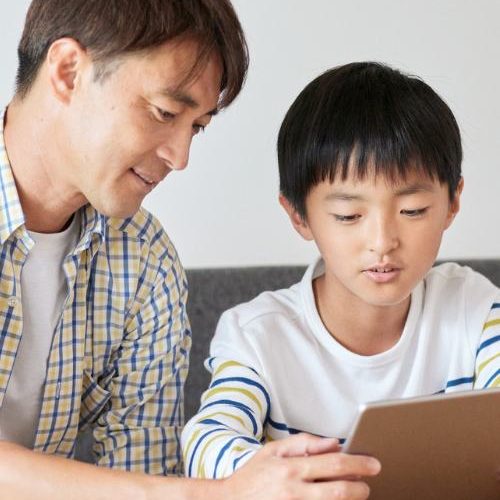 A father and son use a tablet for an online mental health therapy session