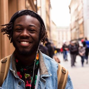 young black man walks through the streets smiling