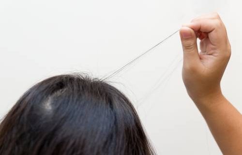 Adolescent girl pulling out strands of hair from their roots