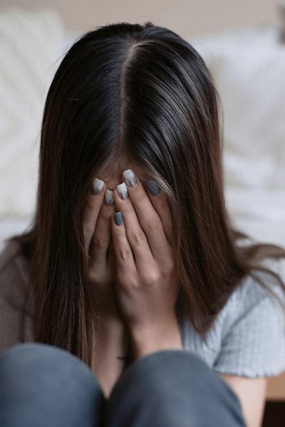 young girl sit at the end of the bed crying due to the struggles of mental health