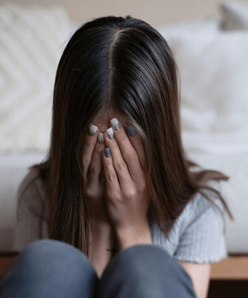 young girl sit at the end of the bed crying due to the struggles of mental health