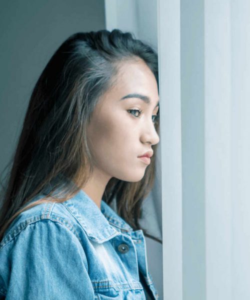 young teen looking out the window struggling with addiction