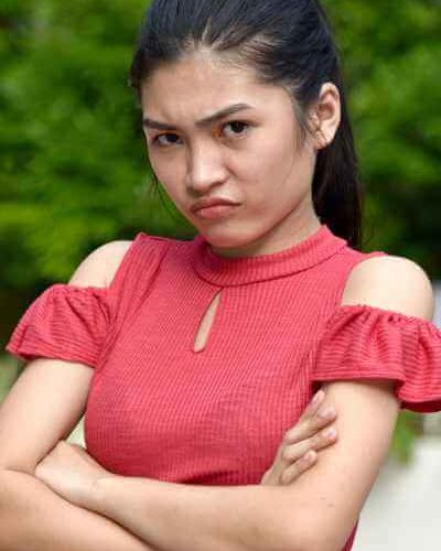 Teen girl with dark hair with folded arms and a facial expression of dismay