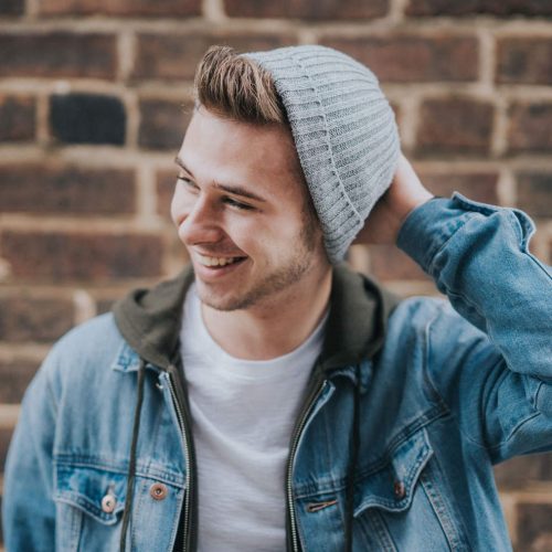young man with beanie smiles as he learns tools to handle mental health