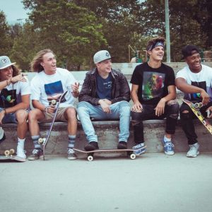 group of young teenage boys sitting on cement wall while skateboarding