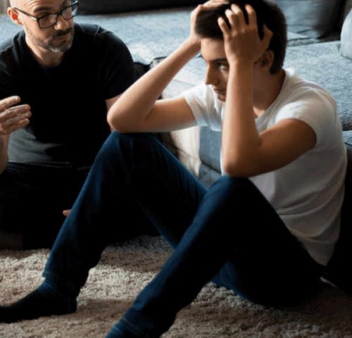 therapist and patient sit on the floor as the patient is having a mental health crisis