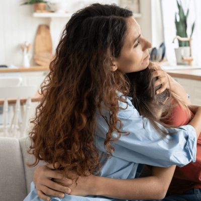 woman hugs her young teen child as they struggle with addiction