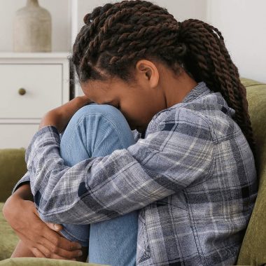 young girl with head in her lap as she struggles with mental health issues